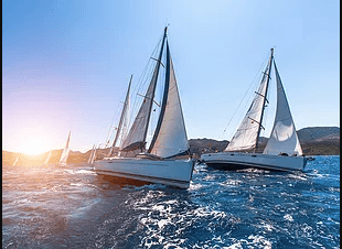 Sailboats racing on open ocean at sunset, scenic coastal cruise