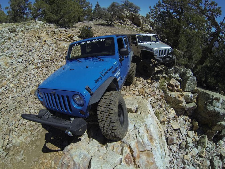 Blue Jeep angled on rocky ridge showcasing high-clearance trail