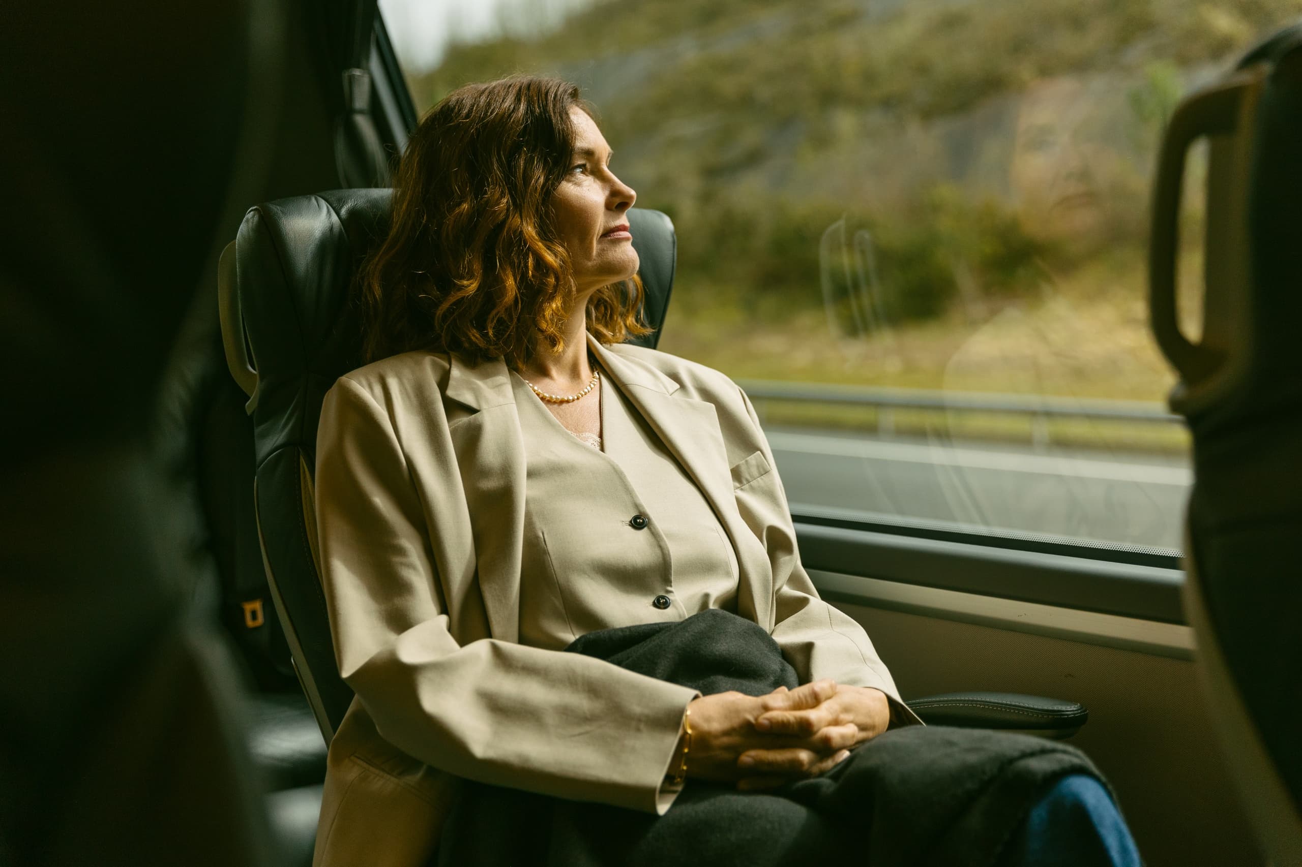 Passenger gazing from train window at passing rural landscape