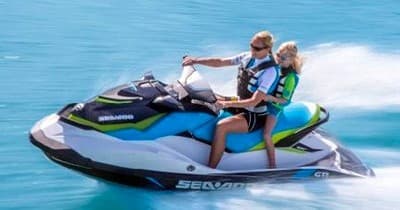 Two riders on jet ski speeding across turquoise open water, thrill