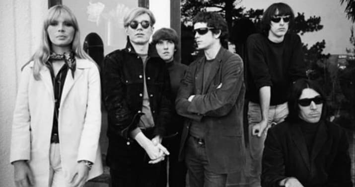 Vintage rock band posing outdoors beside leafy backdrop in NYC