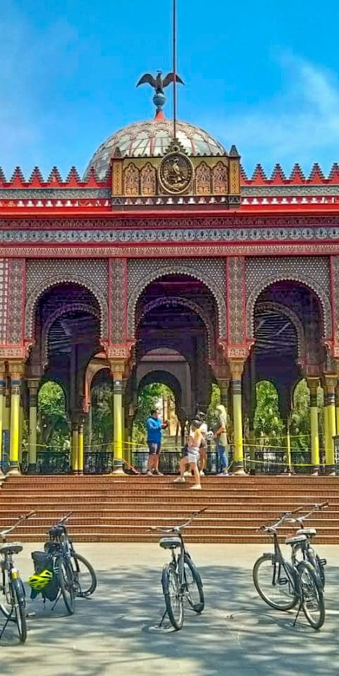 Colorful historic pavilion with parked bikes at sunny plaza