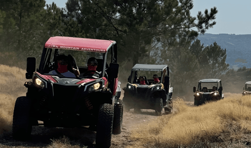 Off-road UTV convoy kicking dust on grassy hill trail