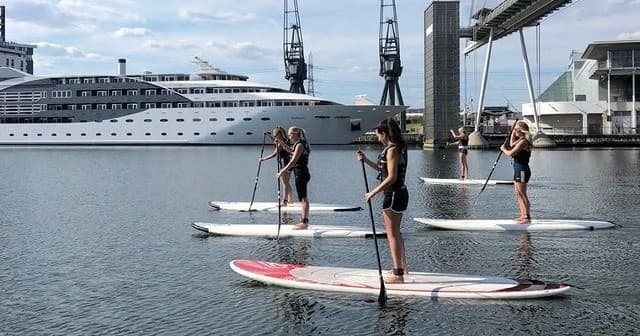 Standup paddleboarders touring harbor waters near cruise ship