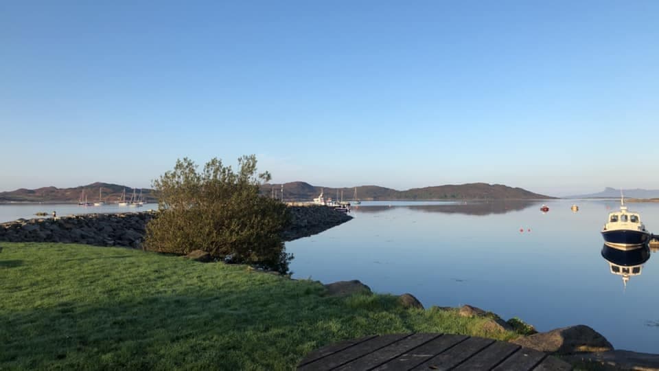 Calm loch with moored boat and reflective shoreline sunrise