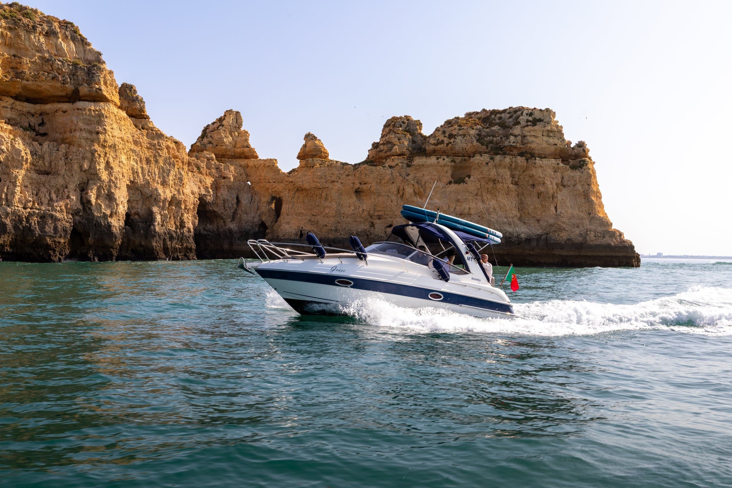 Powerboat cruising past golden sea cliffs on coastal tour