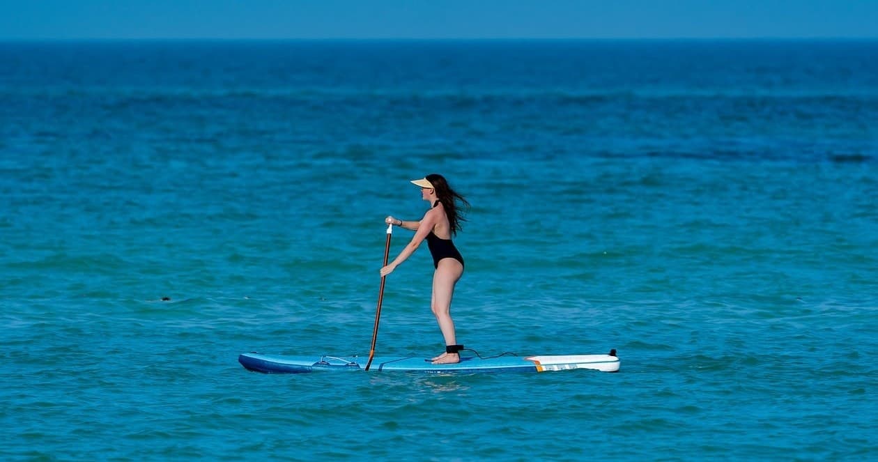 Stand-up paddleboarder cruising on clear turquoise coastal waters