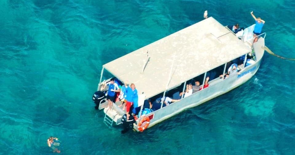 Overhead sightseeing boat anchored on turquoise reef for snorkeling tours