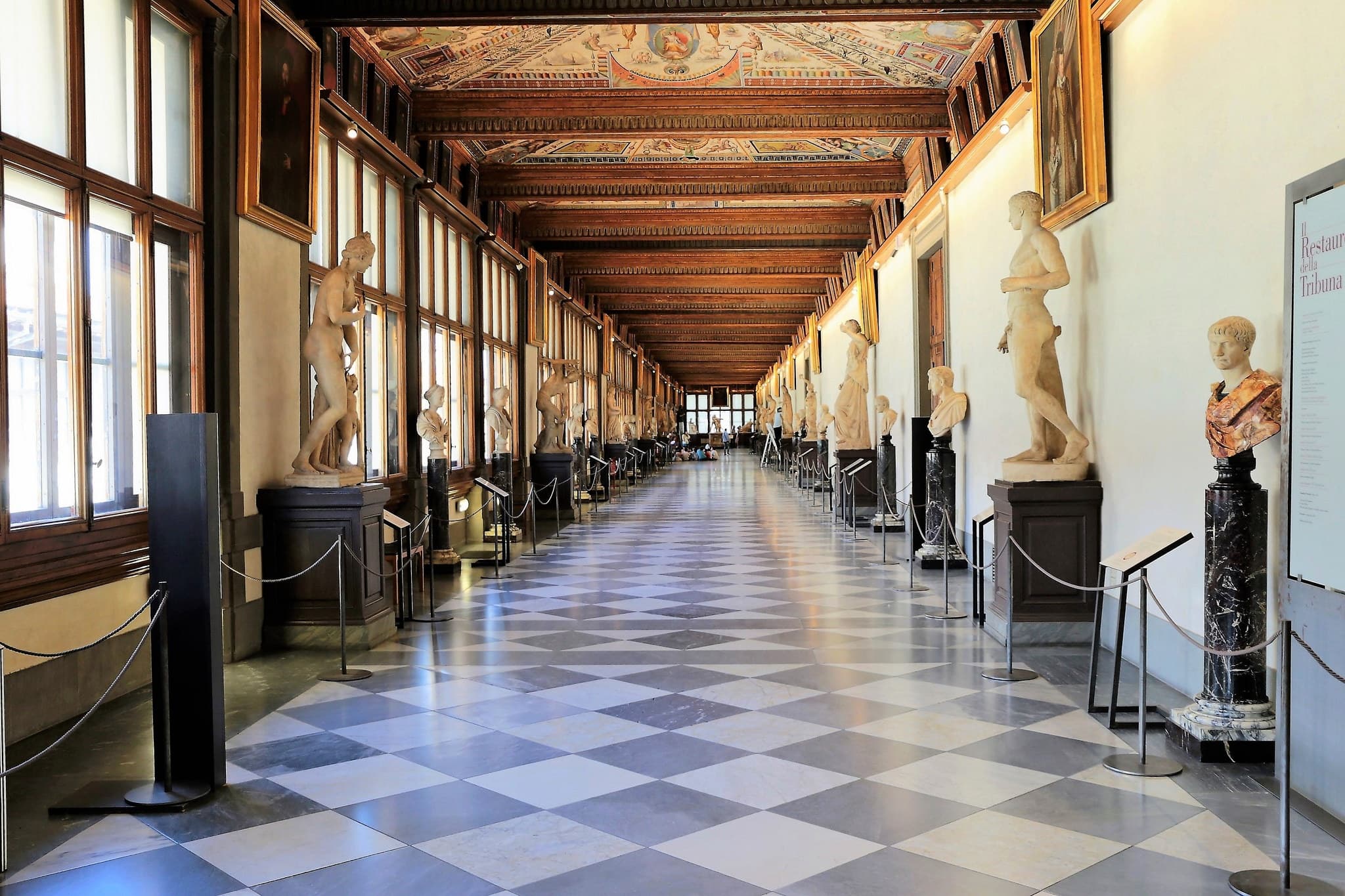 Uffizi-style gallery corridor lined with sculptures, museum walk