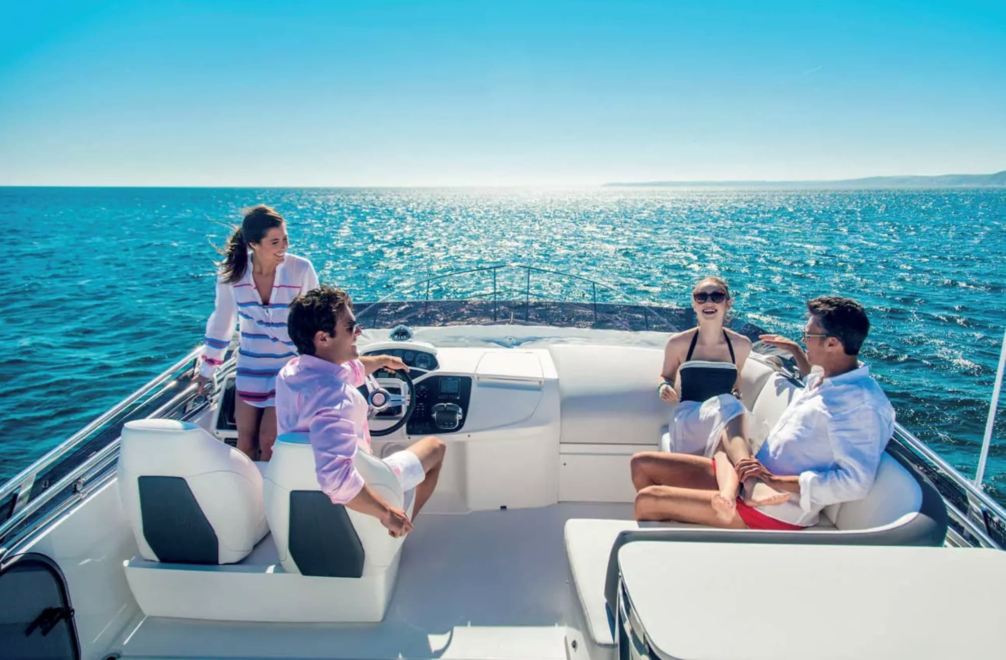 Friends relaxing on yacht deck under sunny coastal horizon
