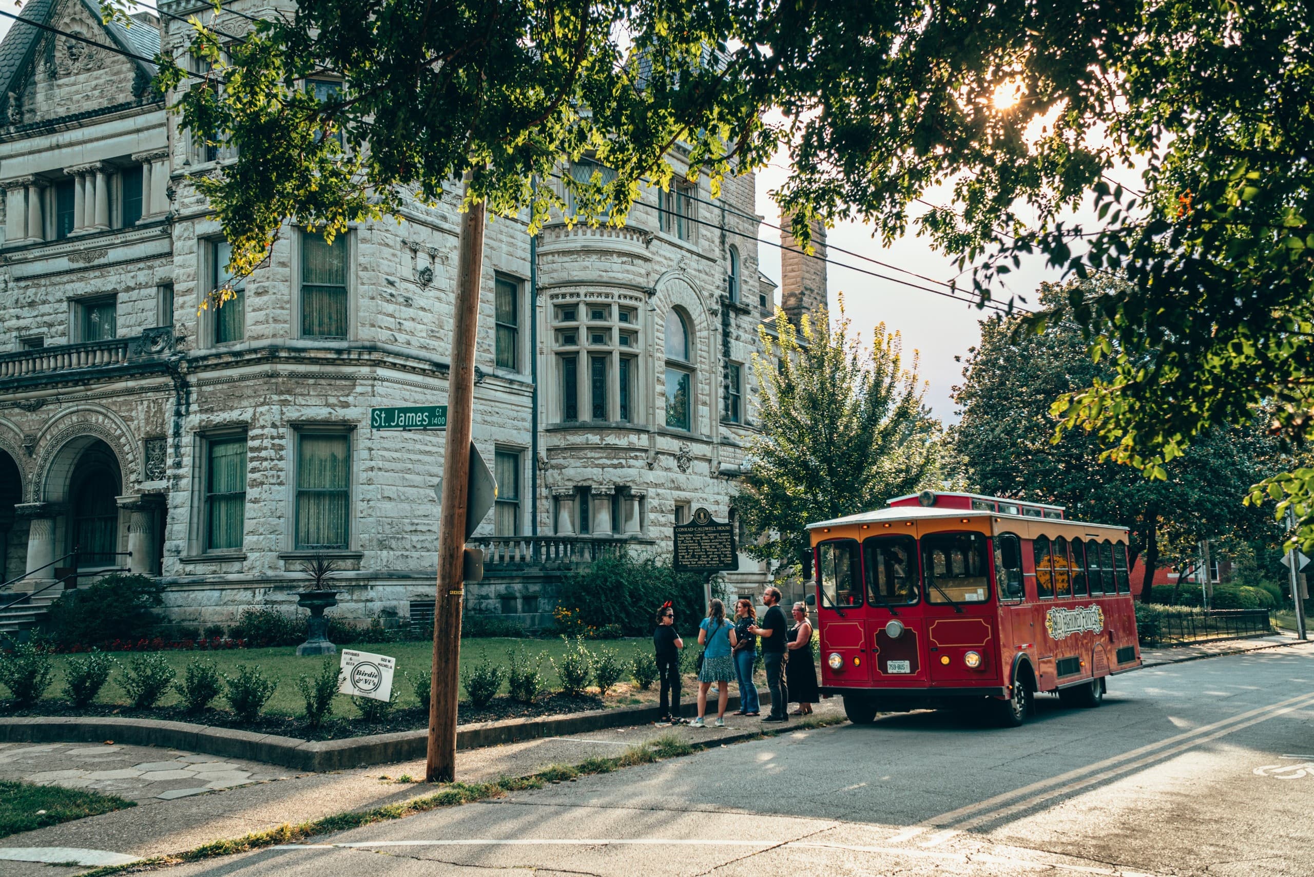 Red trolley rolling past historic city street sightseeing tour