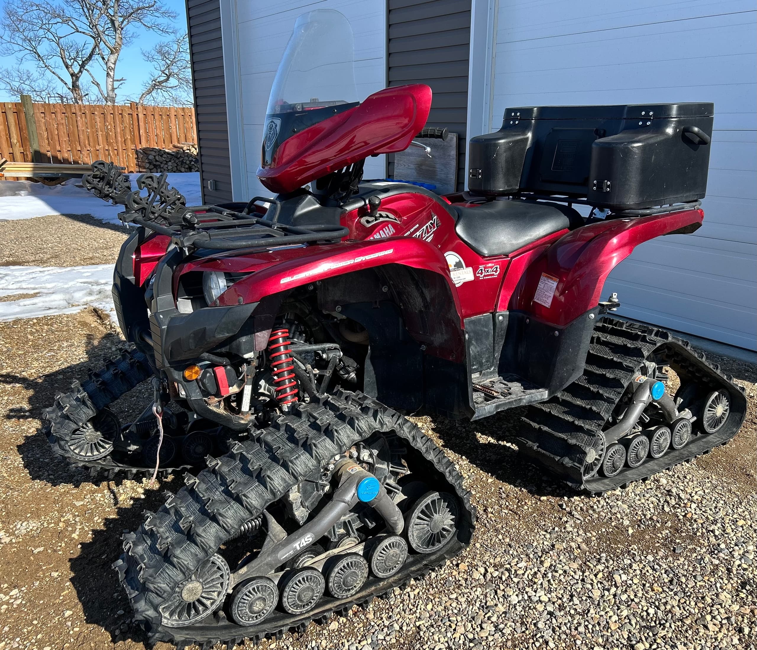 Red ATV with snow tracks staged outdoors for winter riding