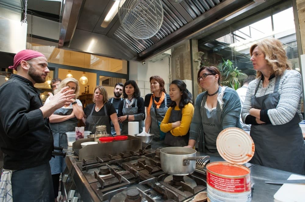 Florence cooking class demonstration over stovetops, group listening