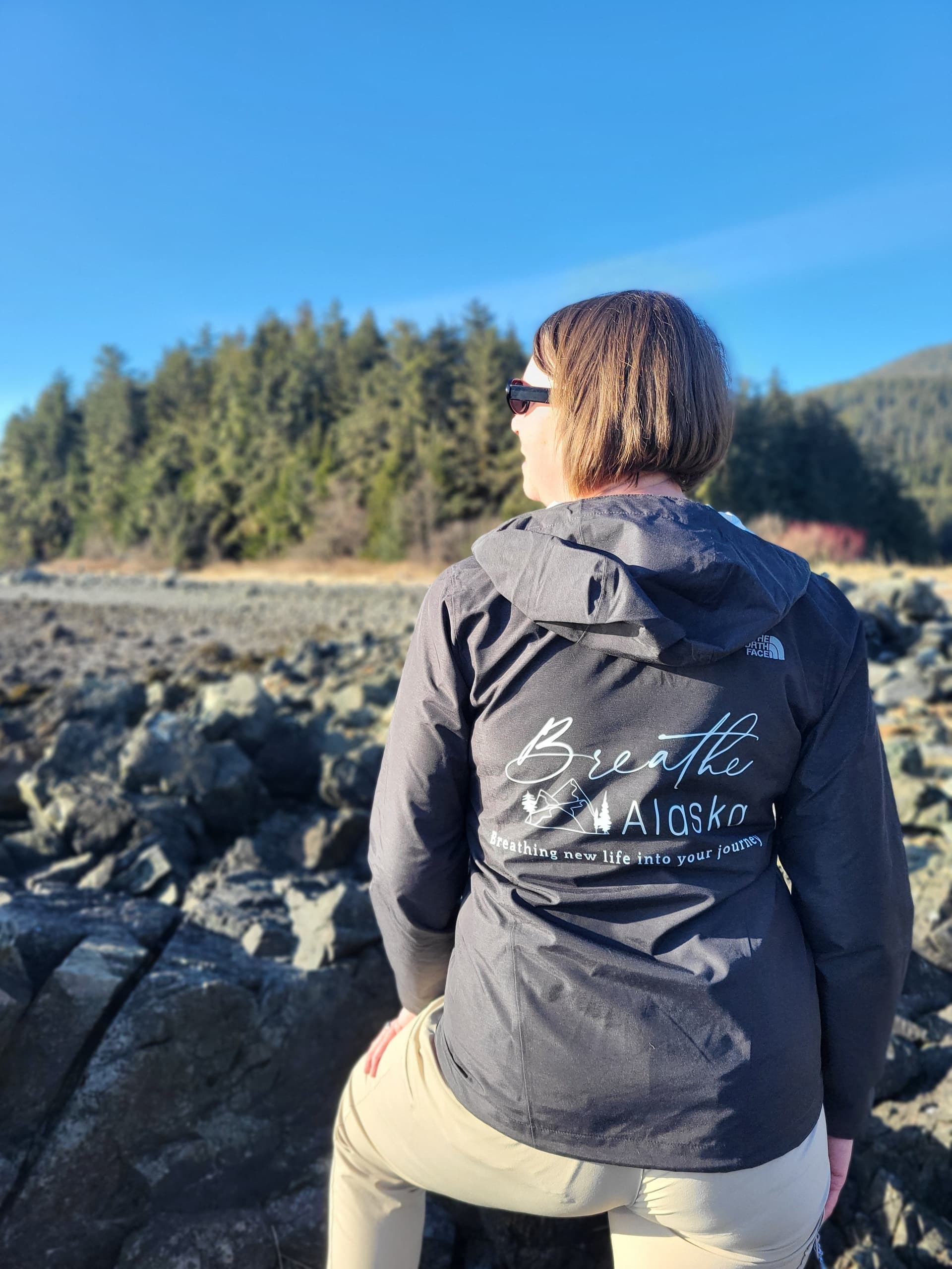 Person overlooking rocky Alaskan shoreline in Breathe Alaska jacket