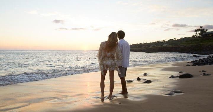 Couple walking on Hawaiian beach at sunset, romantic stroll