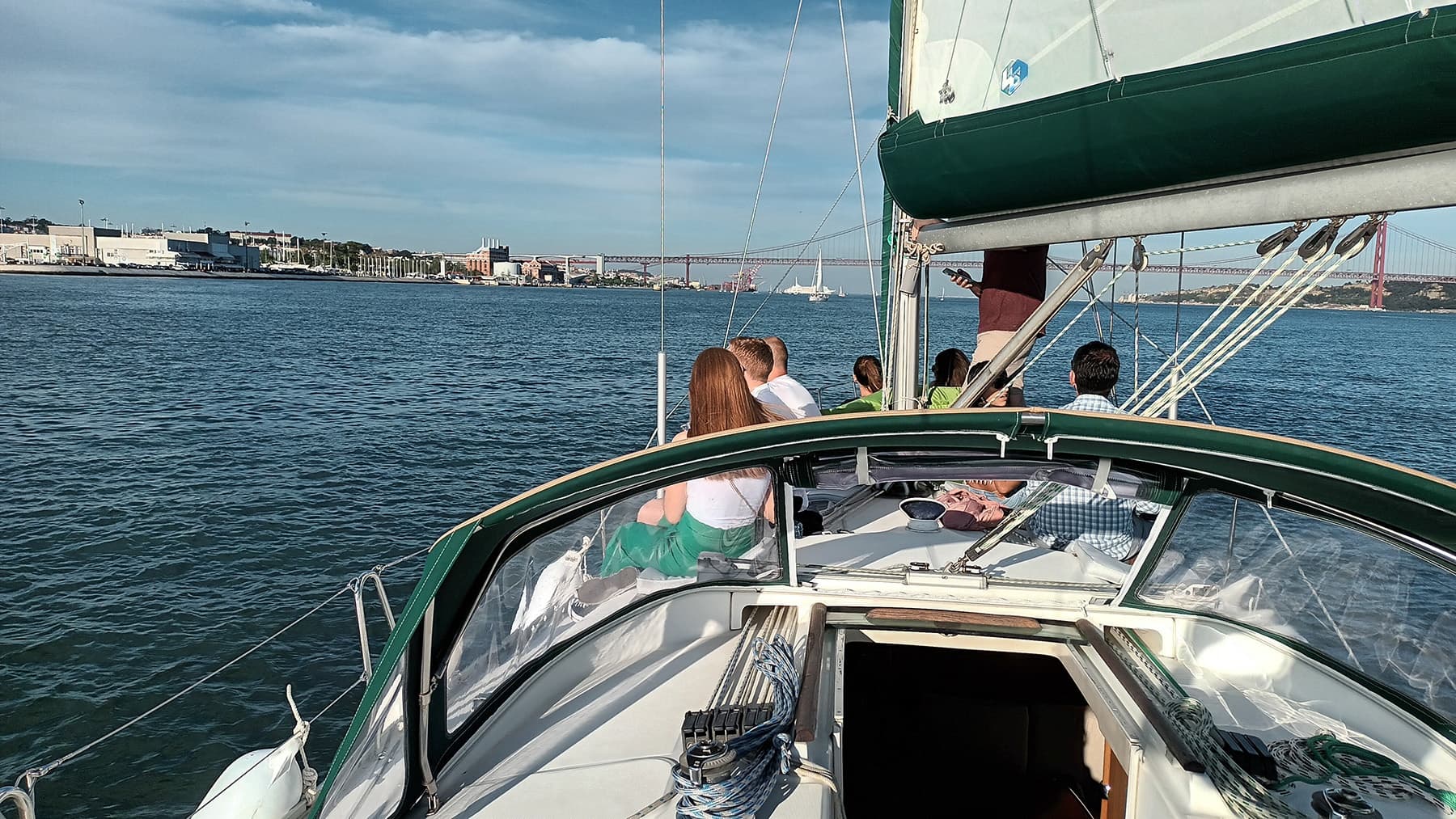 Passengers on sailboat cockpit cruising through coastal harbor