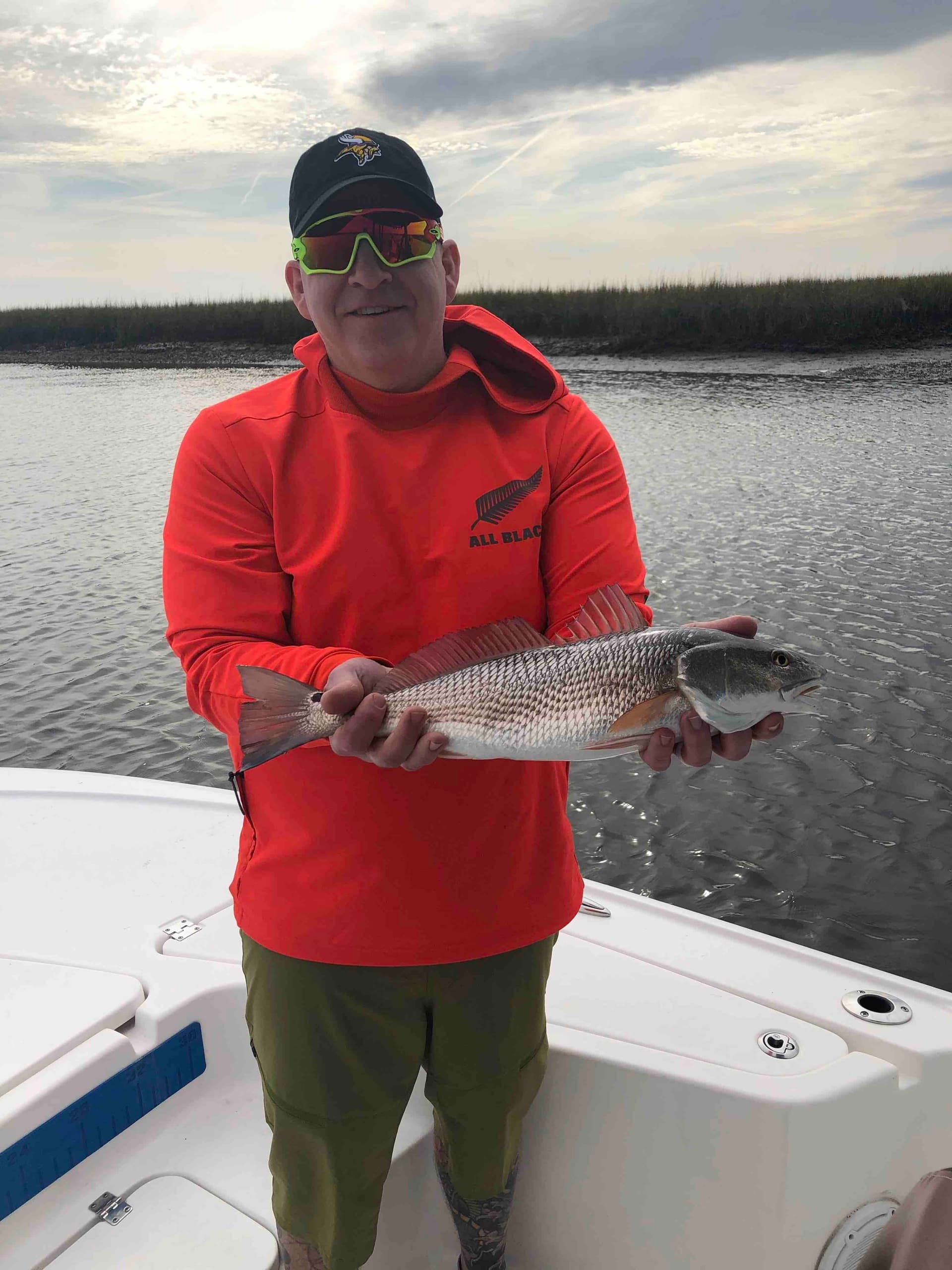 Angler holding redfish on charter boat in coastal marsh fishing