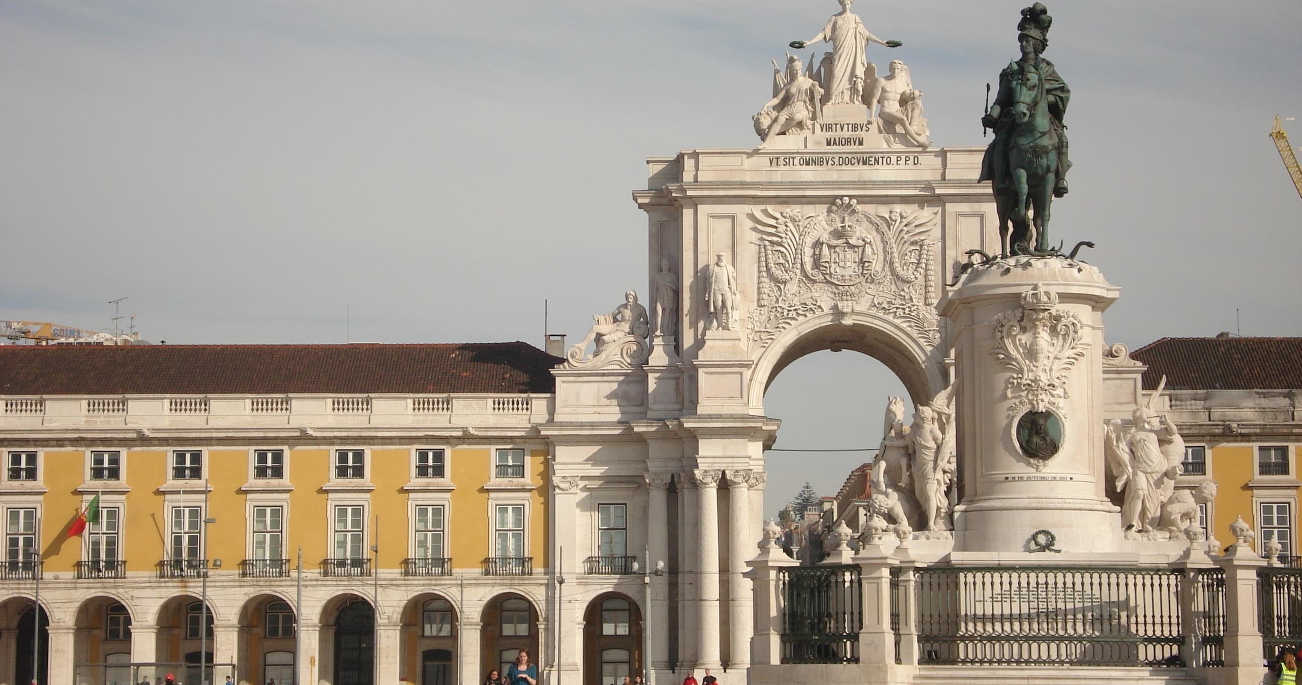 Historic city plaza and triumphal arch under clear sky