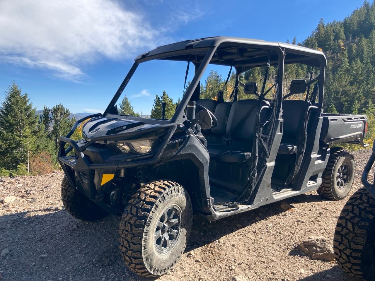 Four-seat UTV parked on mountain trail under blue sky