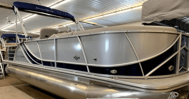 Silver and navy pontoon boat displayed in covered storage bay