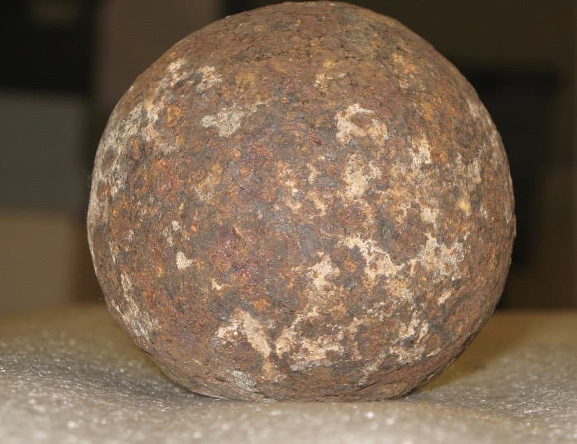 Rusty iron cannonball on indoor museum display for visitors