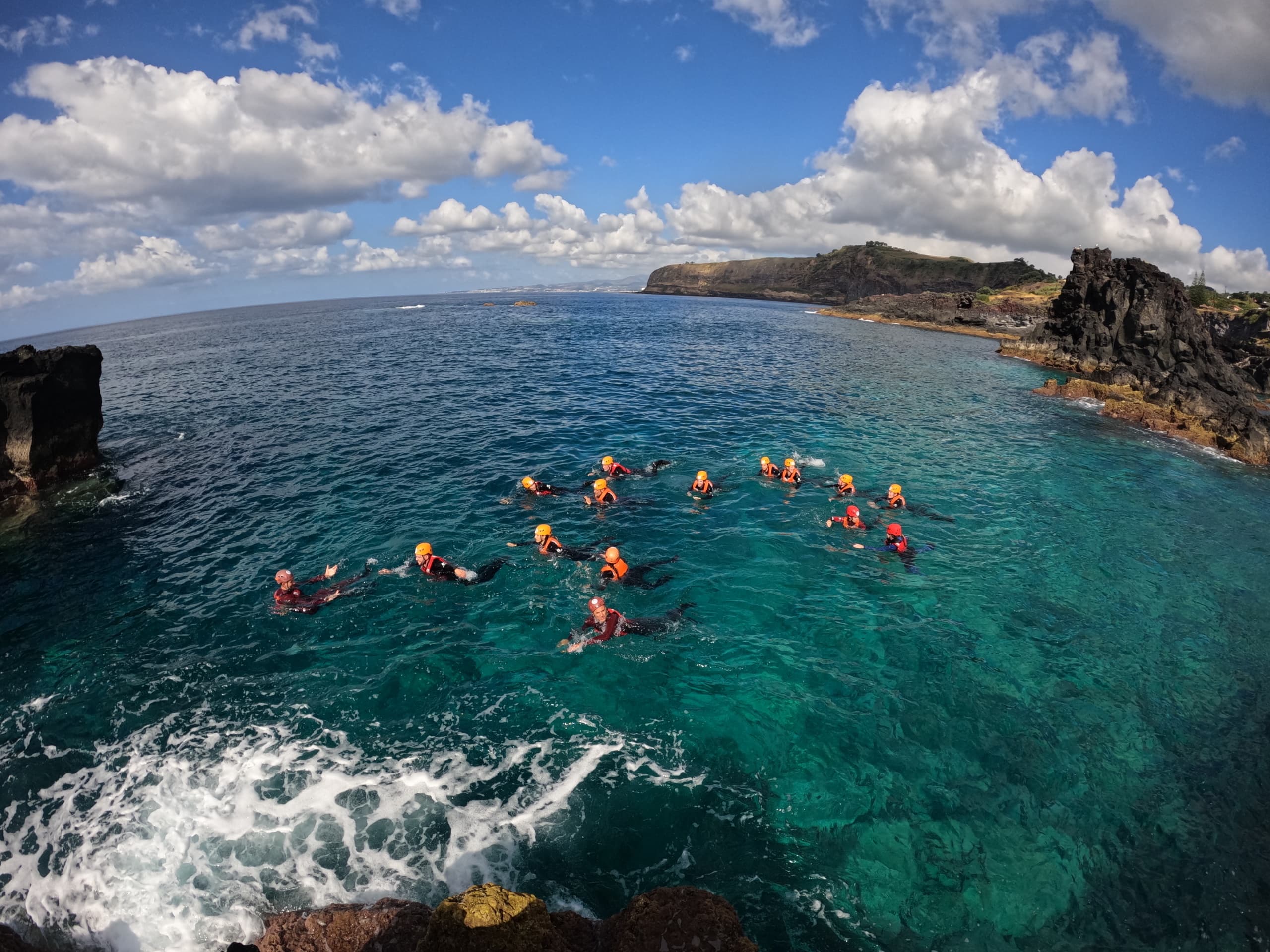 Snorkelers in clear Atlantic waters near rocky Azores coastline