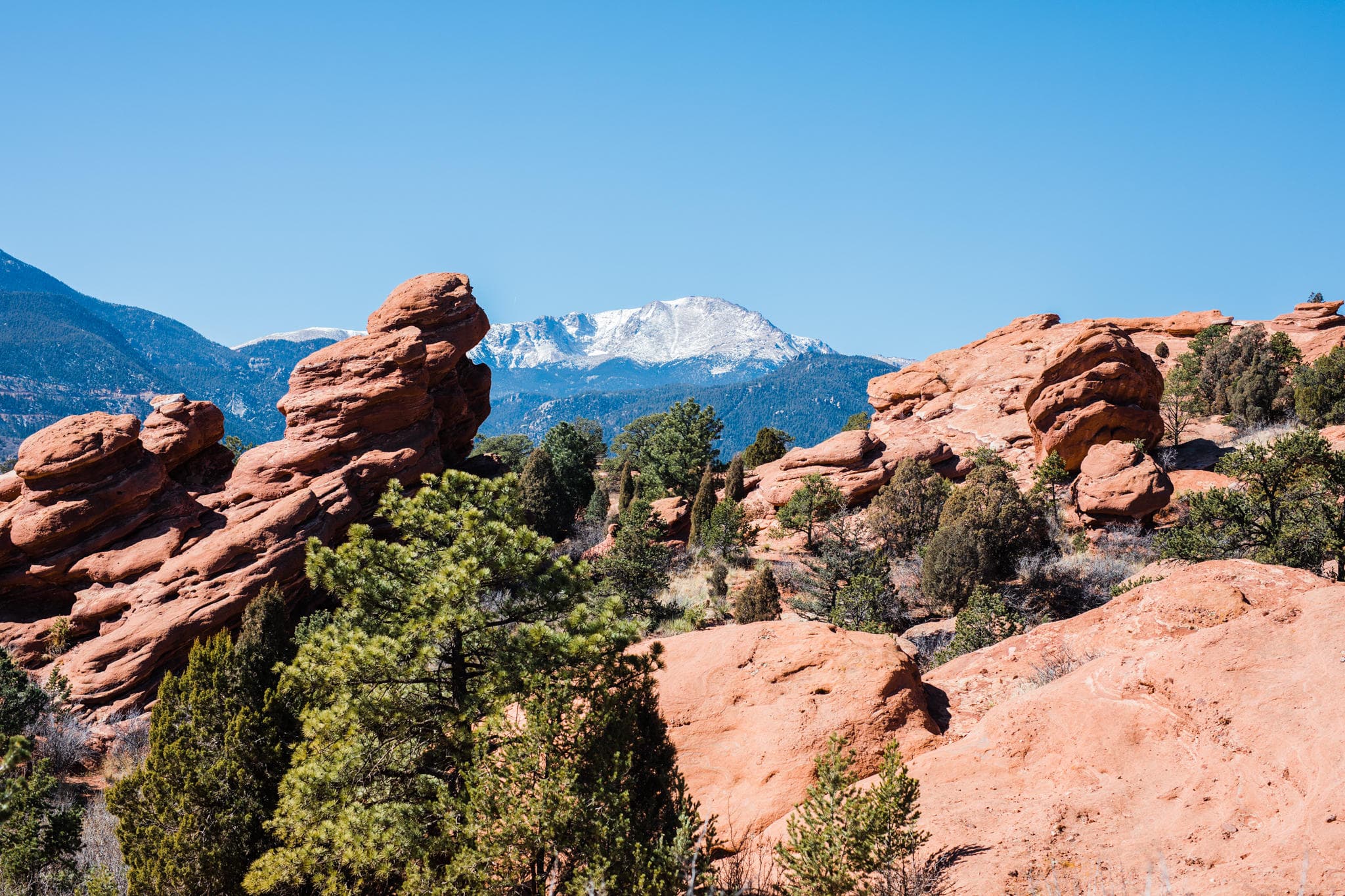 Vast red rock landscape with riders and distant mountain peaks