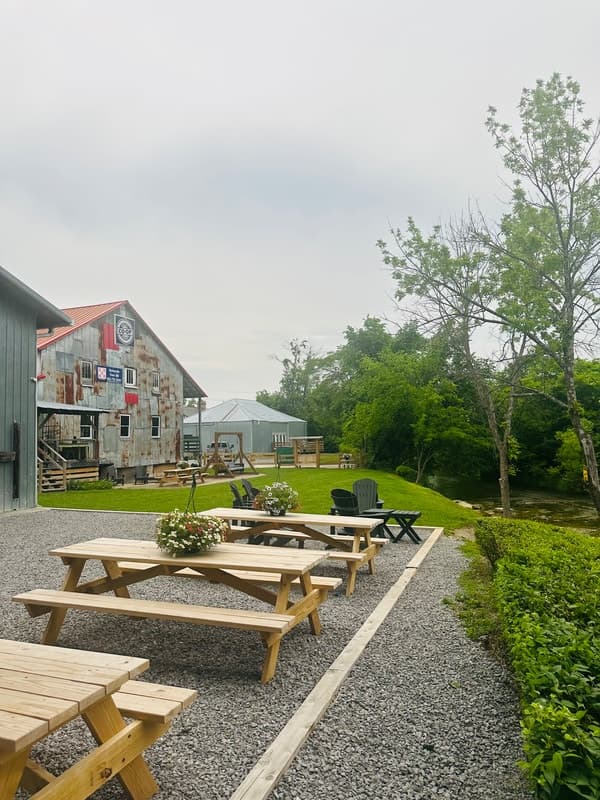 Picnic tables beside rustic feed mill along shaded riverside