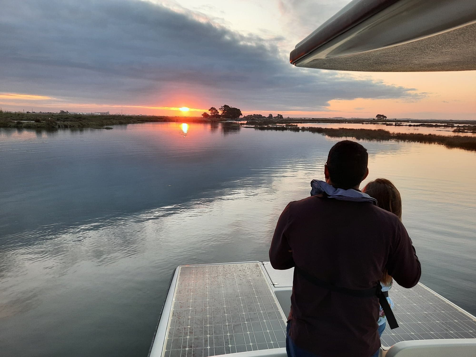 Couple watching sunset from boat over tranquil estuary waters