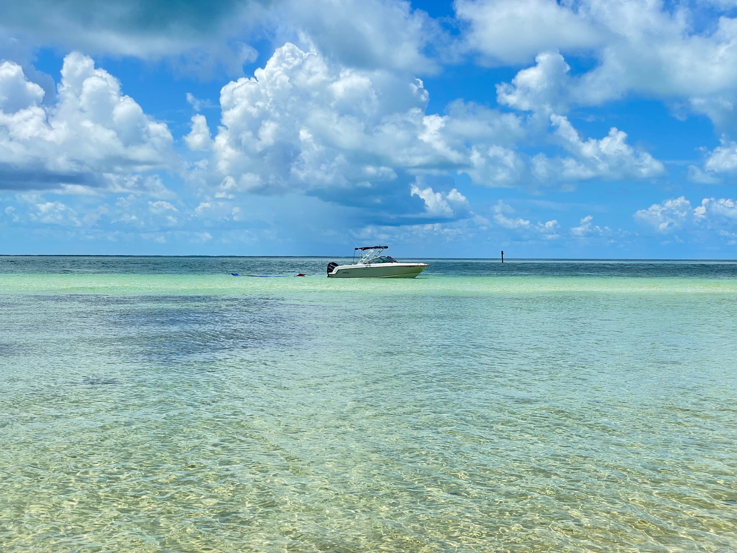 Scenic shallow sandbar with distant boat under dramatic clouds