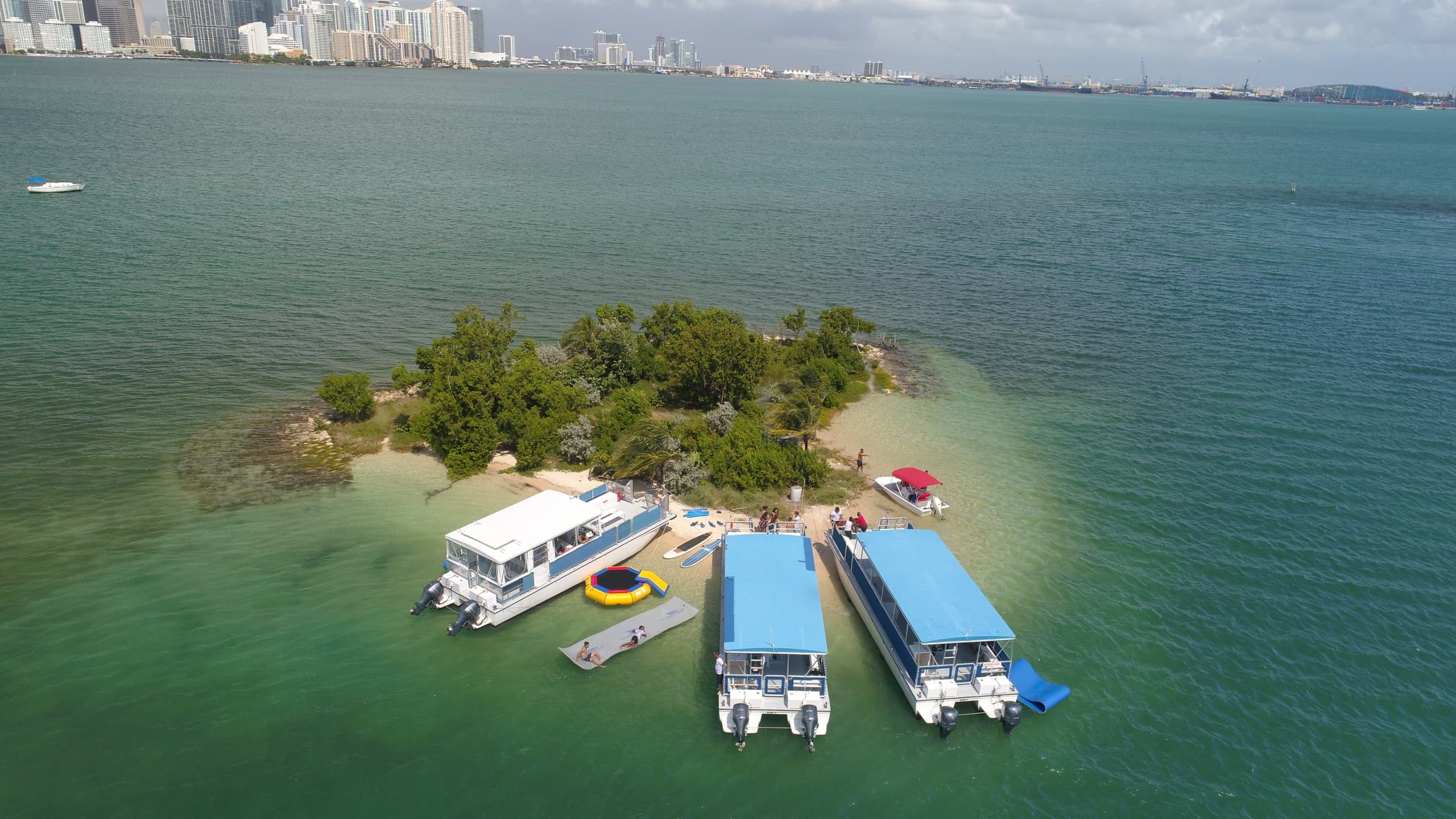 Aerial island sandbar with anchored party boats in turquoise bay