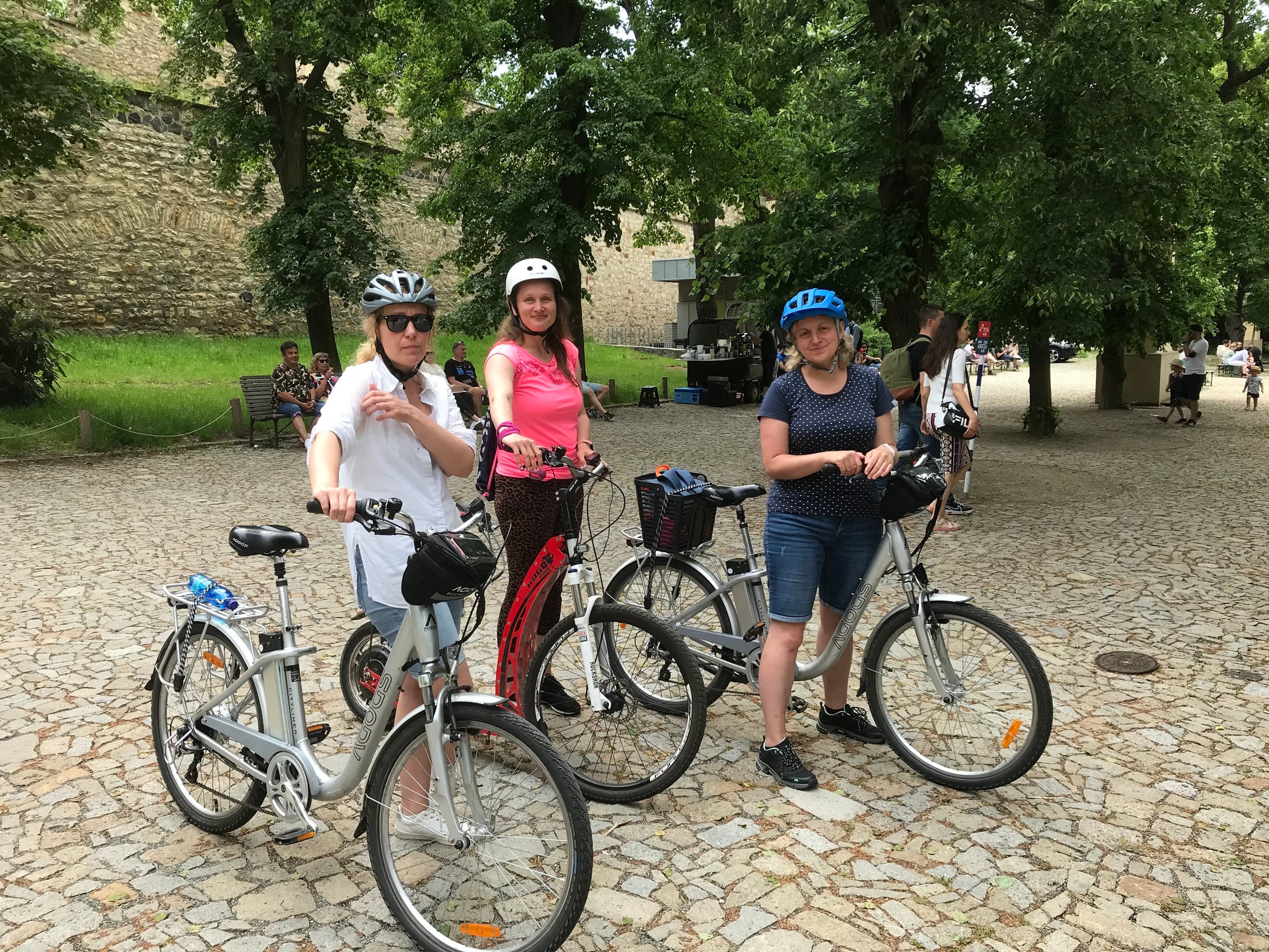 Cyclists posing on cobblestone path near Prague park, bike tour