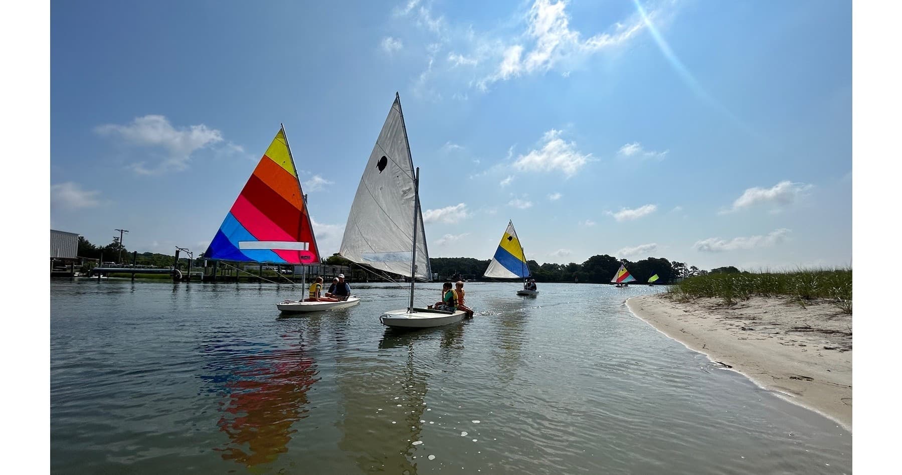 Colorful sailboats sailing off Cape Charles shoreline in summer