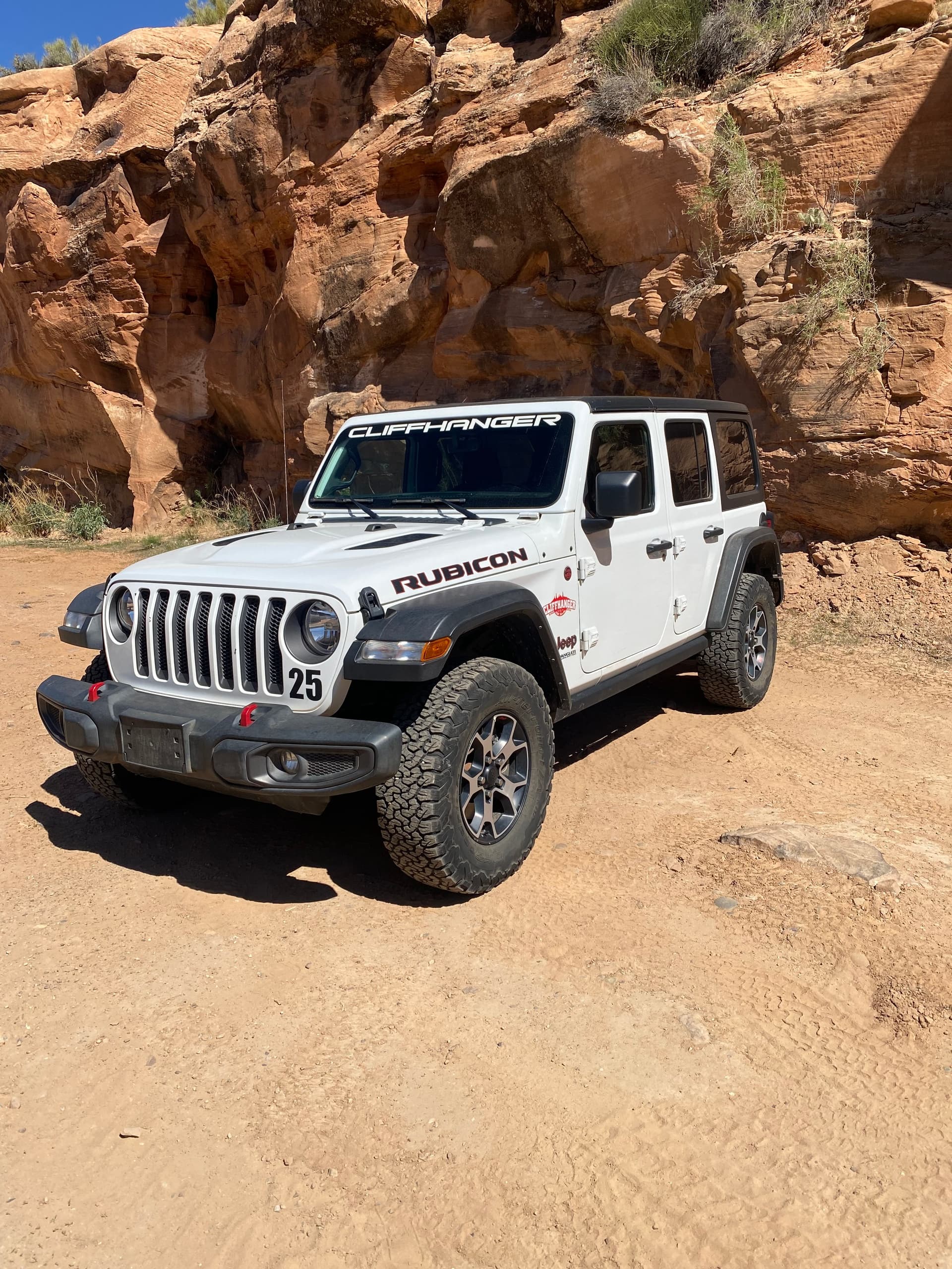 White Jeep Wrangler parked amid red rock vistas on desert trail