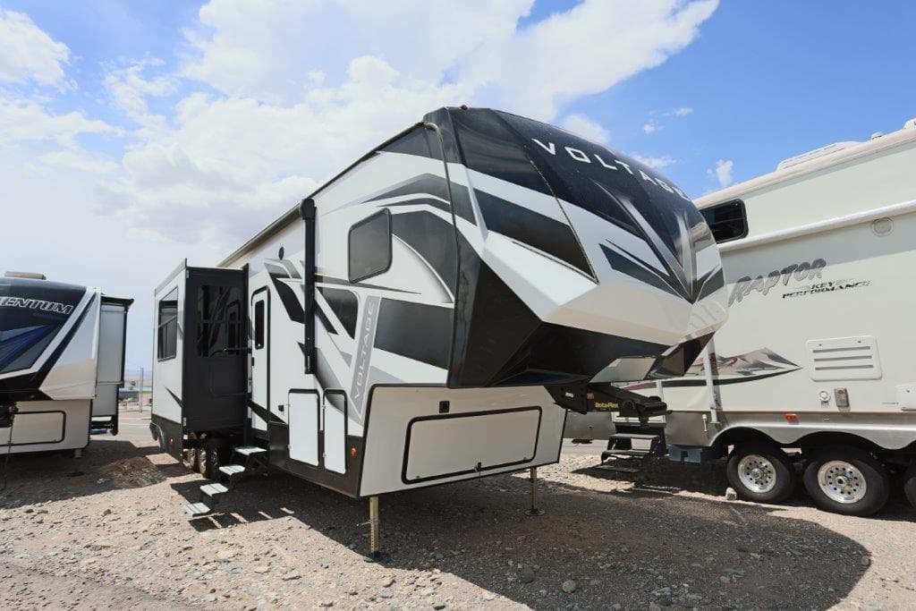 Luxury fifth-wheel RV with slide-outs parked at sunny RV lot