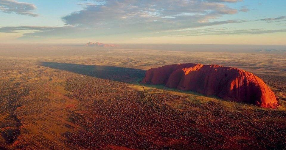 Sunrise scenic flight showing Uluru casting long shadow over outback