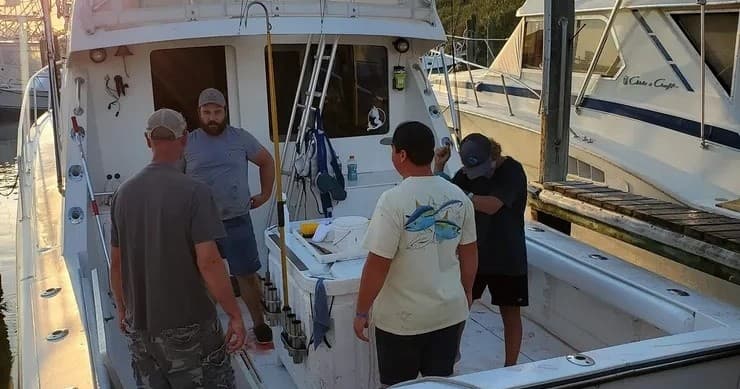 Crew prepping gear aboard sportfishing boat at marina dock