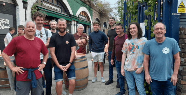 Brewery tour group standing by barrels outdoors at craft brewery