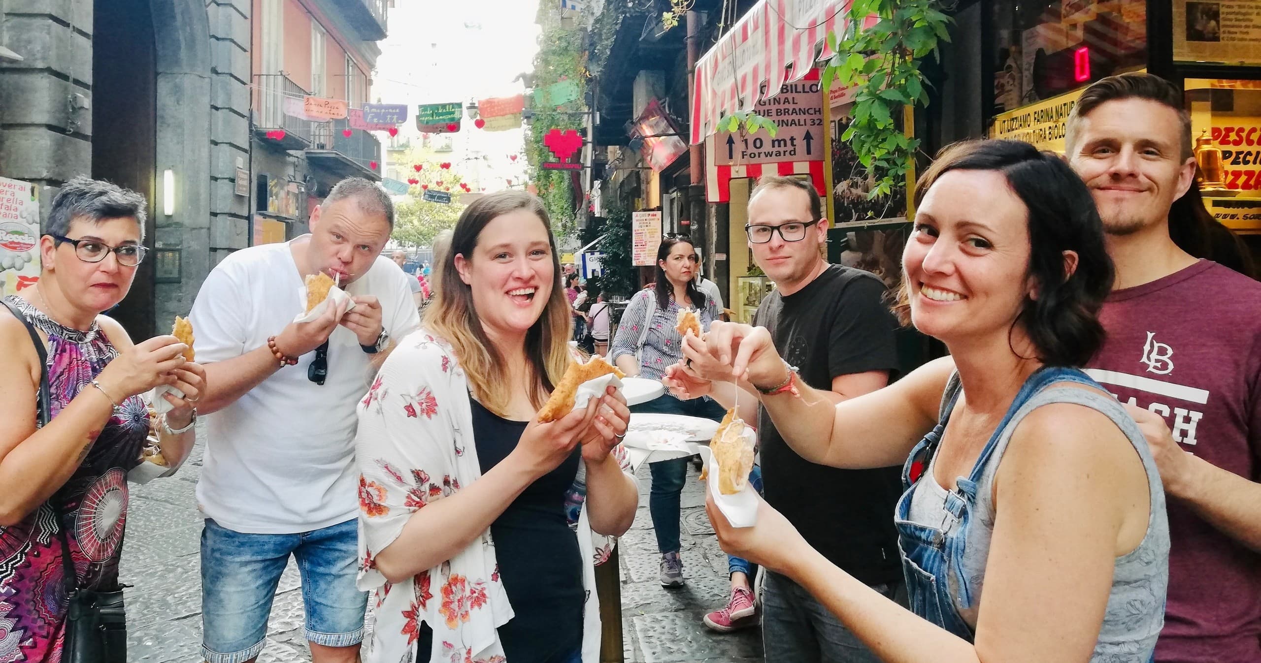 Street food tasting with group in lively narrow Italian alley