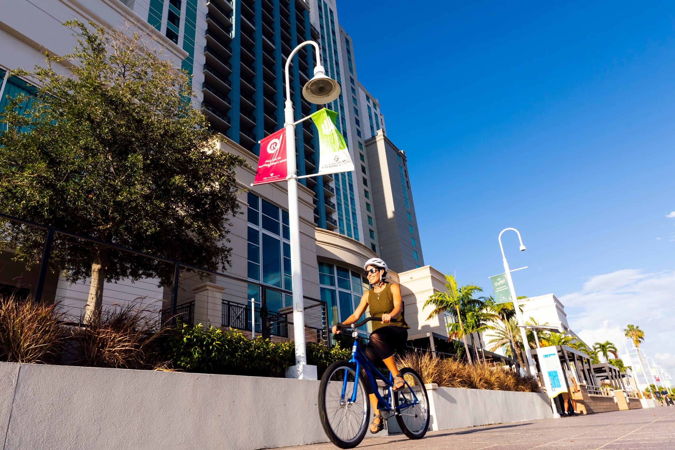 Cyclist riding along sunny riverwalk promenade by downtown