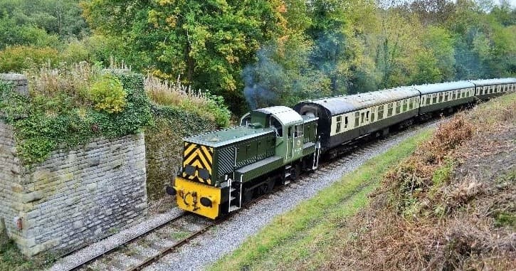 Diesel heritage train crossing stone embankment in valley