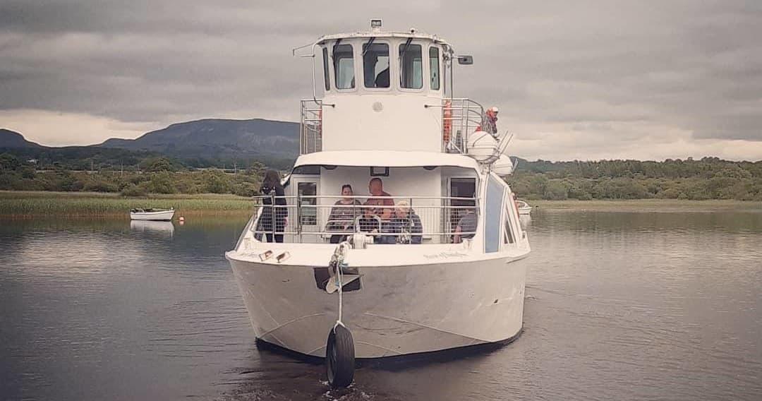 Small yacht anchored on calm inlet with passengers enjoying view