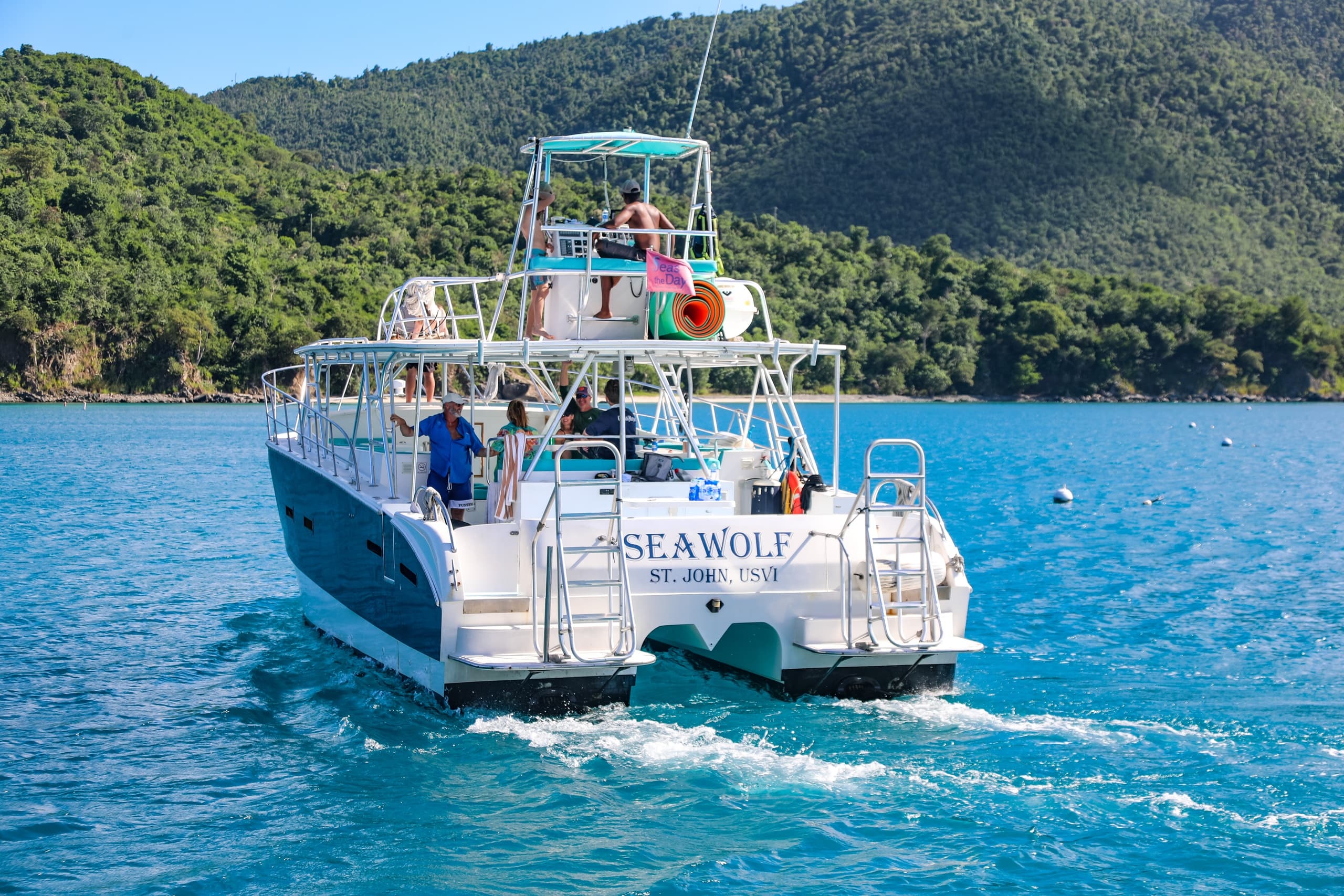Day charter boat cruising clear blue sea with island backdrop