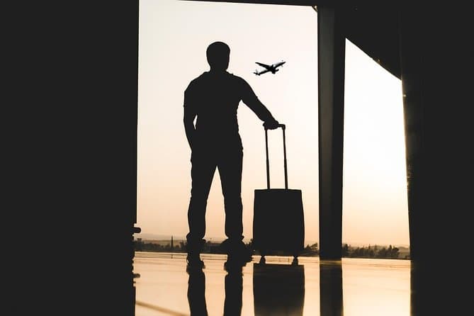 Silhouette traveler watching plane at airport terminal sunset