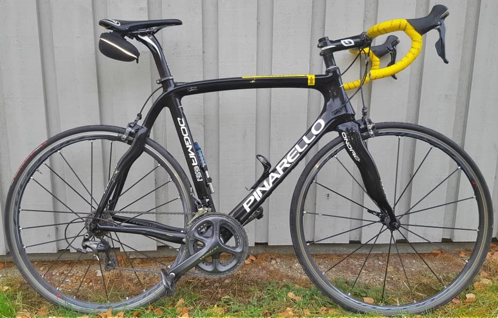 Black road bike parked outdoors near shed, ready for road ride