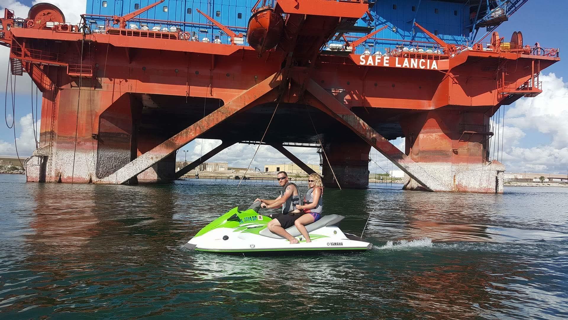 Jet ski riding beneath offshore rig near harbor platform