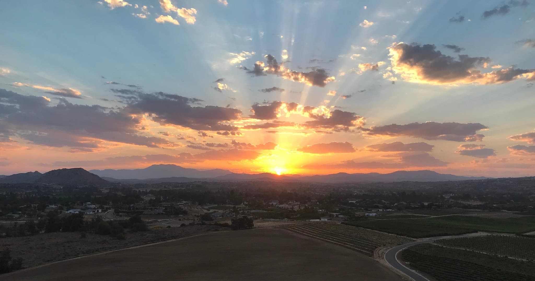 Sunset over valley with dramatic rays and distant hills