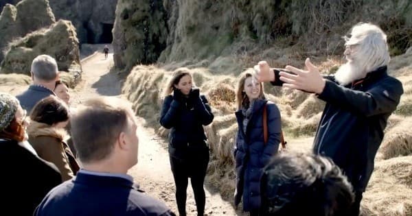 Guided walking tour group exploring coastal cliffs and caves