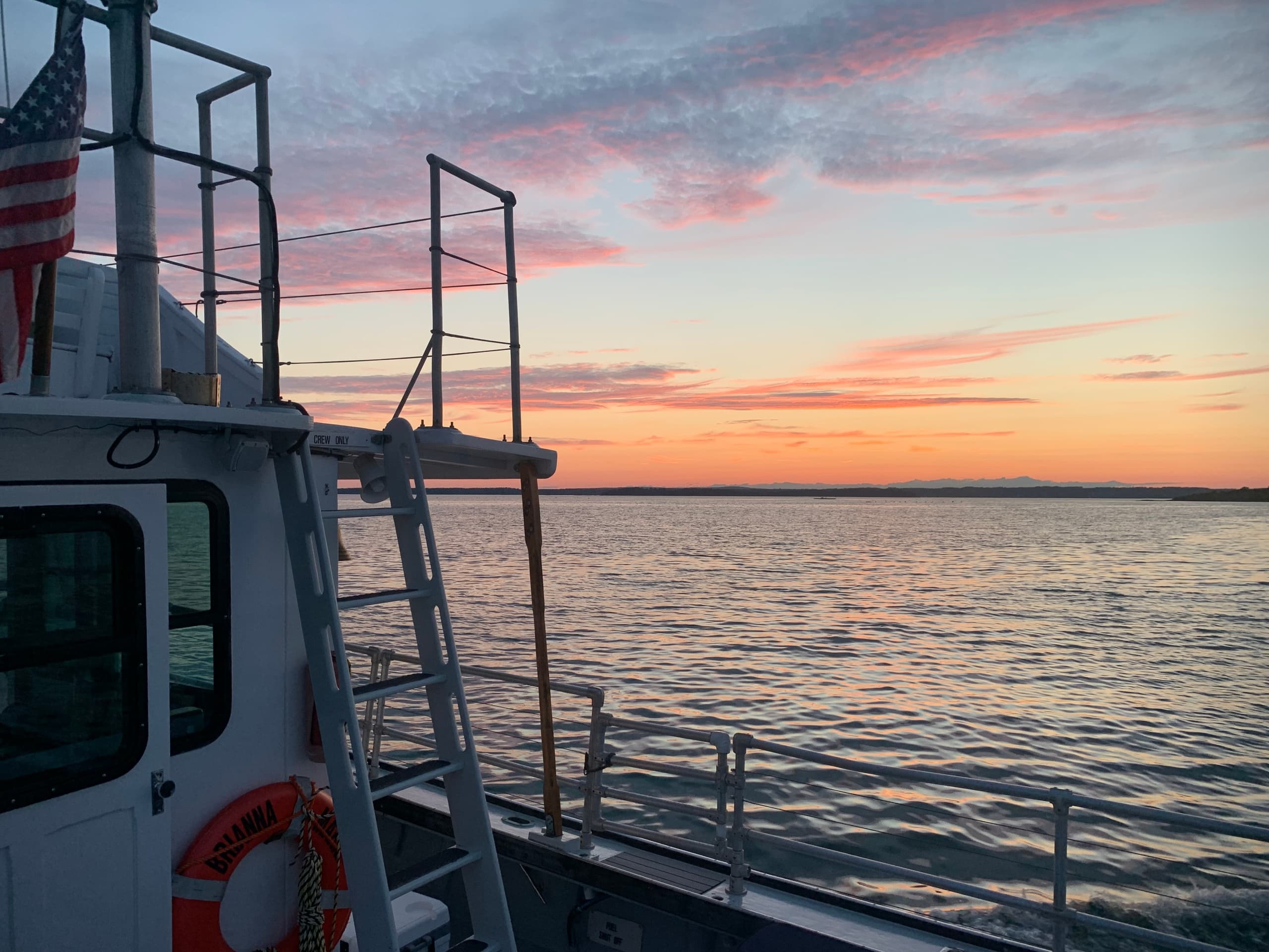 Boat deck at sunset with coastal horizon and calm sea