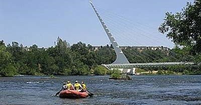 Guided raft with crew passing modern cable-stayed bridge